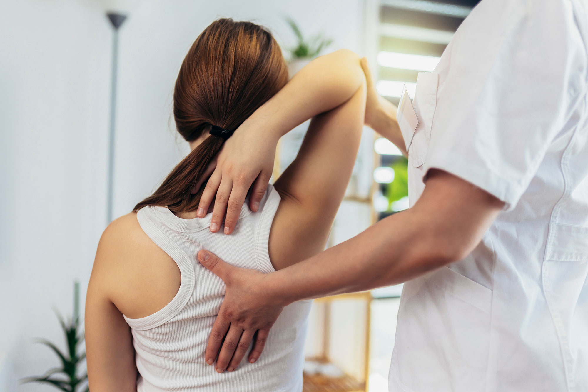 Chiropractor examining a patient's back and shoulder
